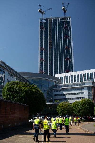 external shot of tall building with cranes on top and blue sky