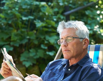 elderly man reading newspaper in the garden